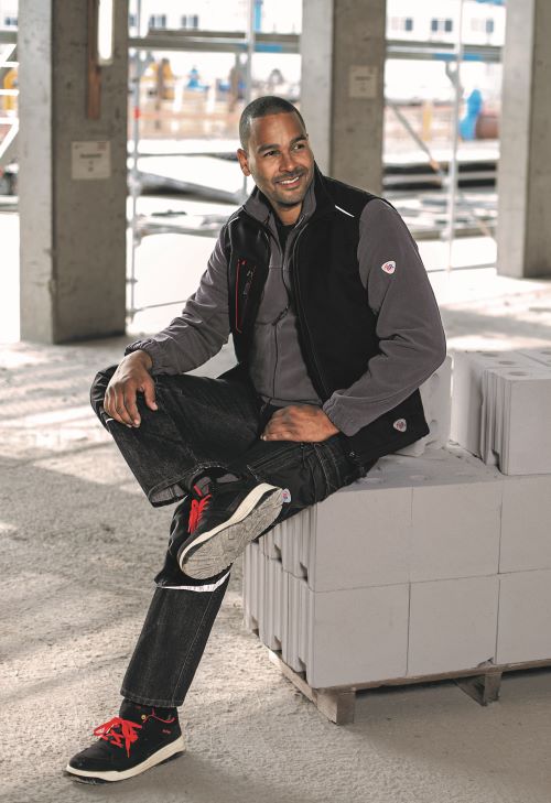 Un homme portant un gilet de travail est assis sur un chantier.